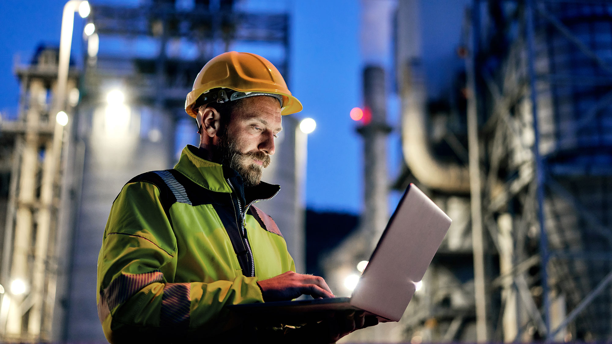 young engineer using a laptop during the night shift at a factory