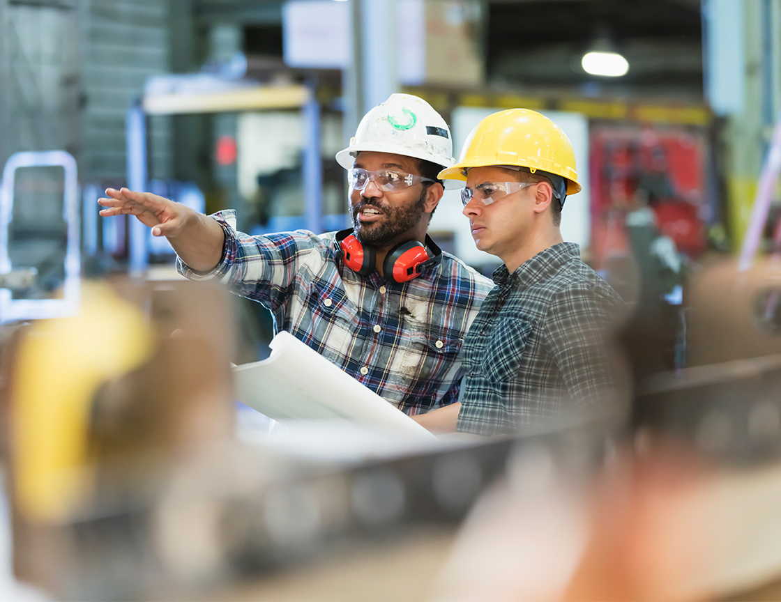 two-men-in-hard-hats-and-safety-goggles-in-warehouse