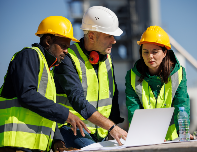 a-woman-and-two-men-looking-at-laptop-wearing-hard-hats-and-safety-vests