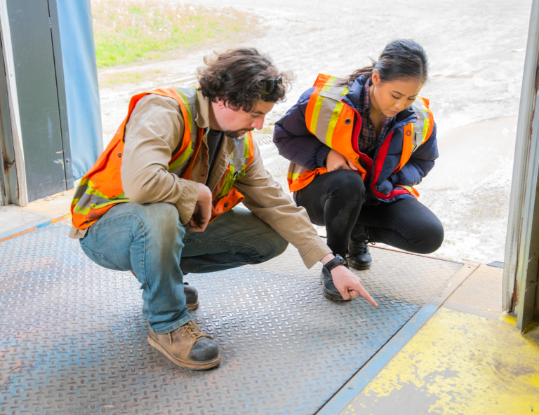 man-and-woman-in-safety-vests-looking-at-ground