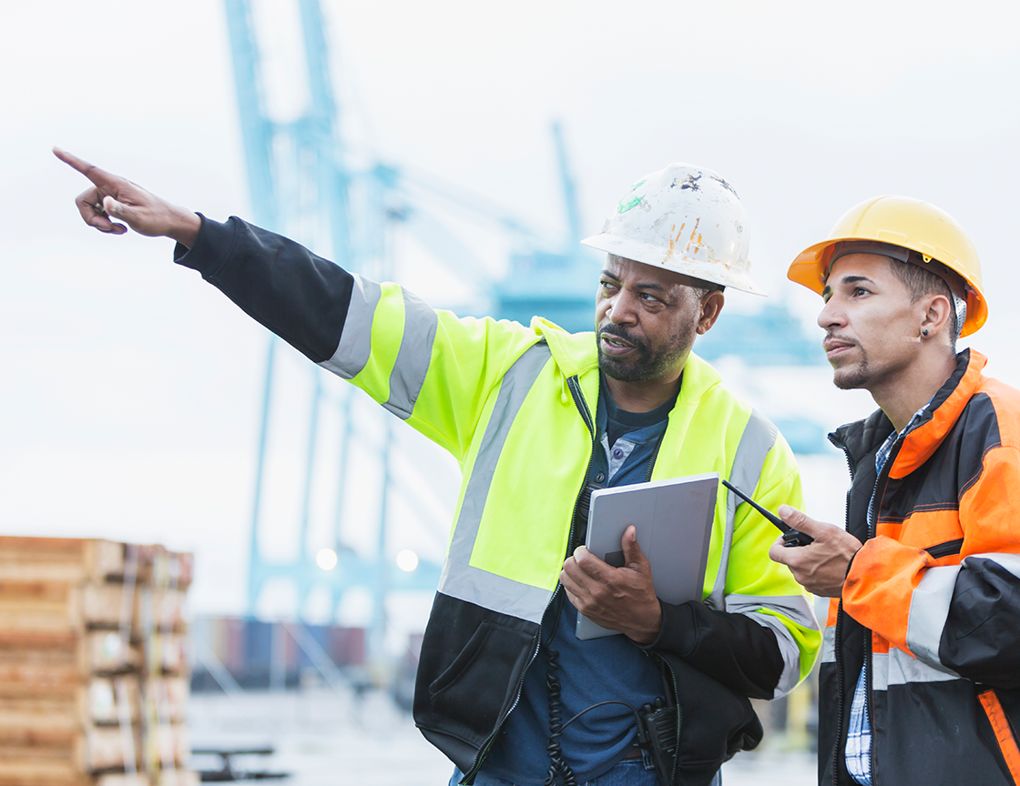 two-men-in-hard-hats-and-safety-vests-looking-away